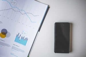 A smartphone next to a book with graphs on it.