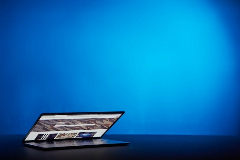 A laptop on a table with a blue background.
