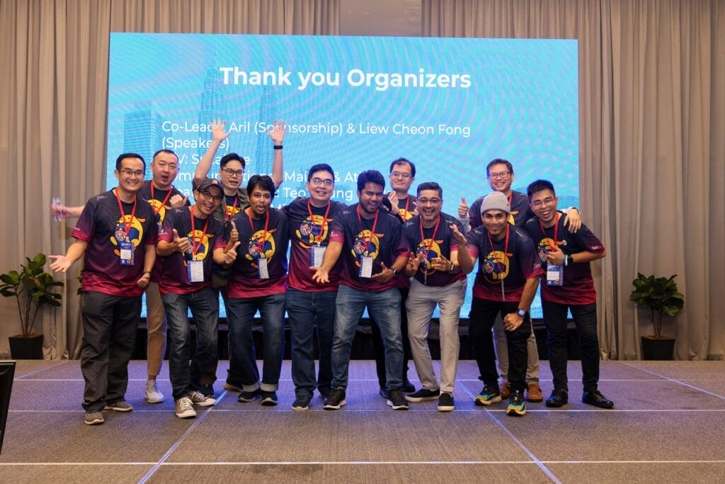 A group of ten people in matching shirts poses on stage, their spirits high, as a screen behind them proudly displays "Thank you Organizers" alongside some names. This heartfelt moment captures the essence of unity and gratitude that resonates throughout the About Leokoo event.