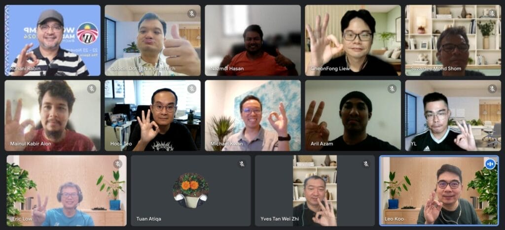 A group of sixteen people in a virtual meeting, each holding up an "OK" hand gesture, with some participants’ cameras turned off or displaying profile pictures.